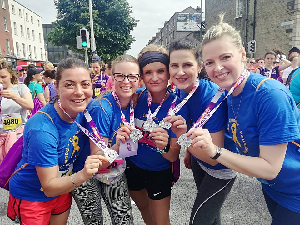 Photo of five women in Childhood Cancer Ireland t-shirts holding out their mini marathon medals.