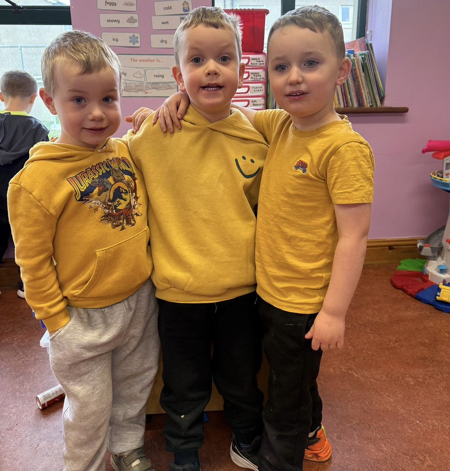 Three small children wearing gold jumpers