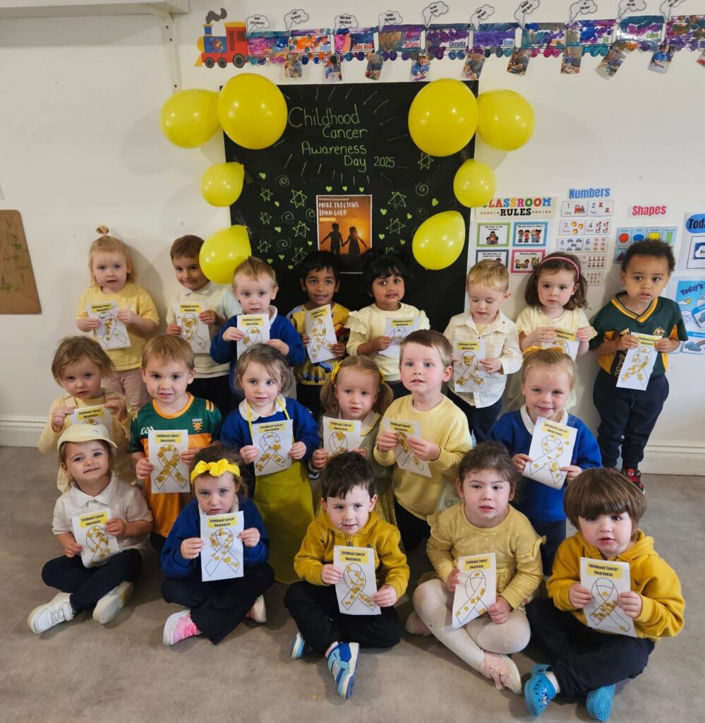 A group of children all dress in yellow holding up colouring pages