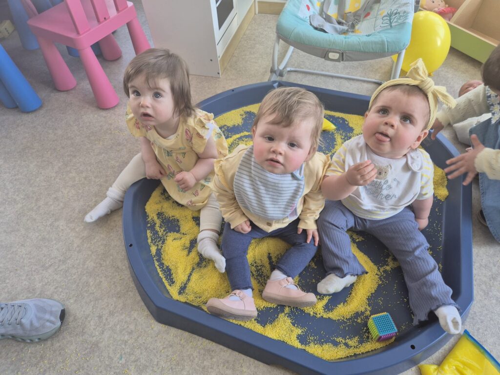 Three small children sitting in a tuff tray